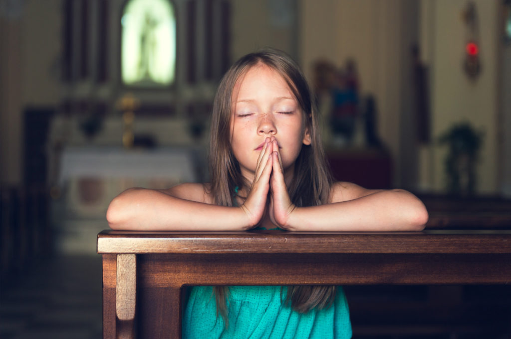 Cute kid girl praying in a church