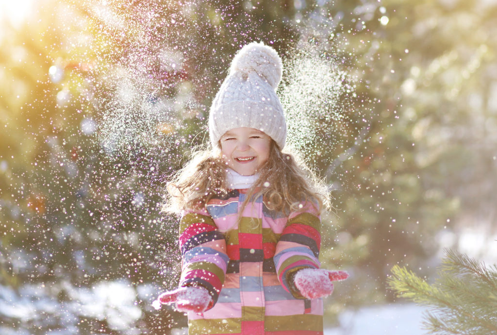 Joyful child having fun with snow in winter day