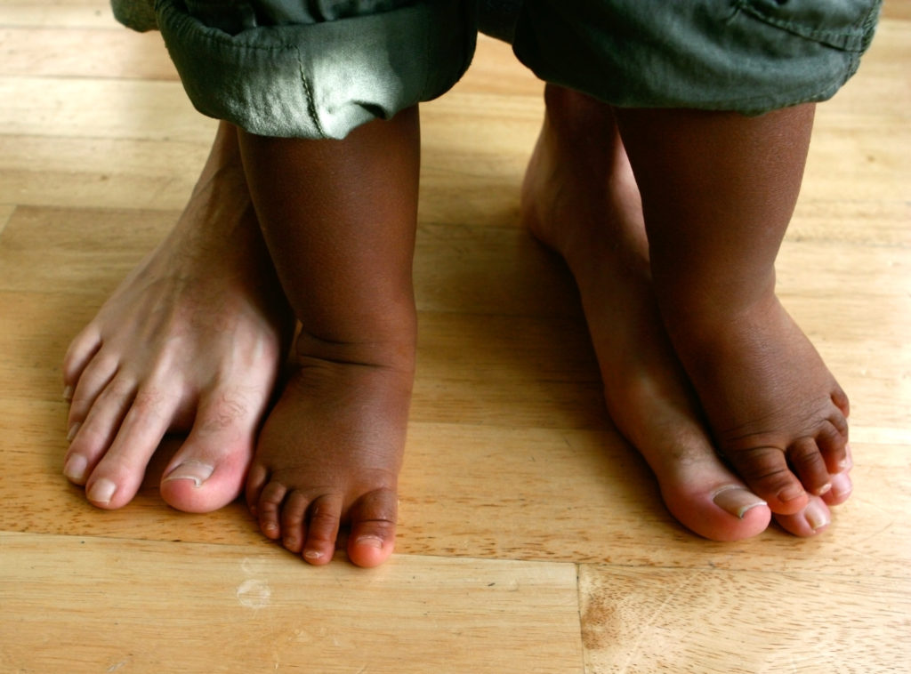 two pairs of feet belonging to a father and his little toddler son.
